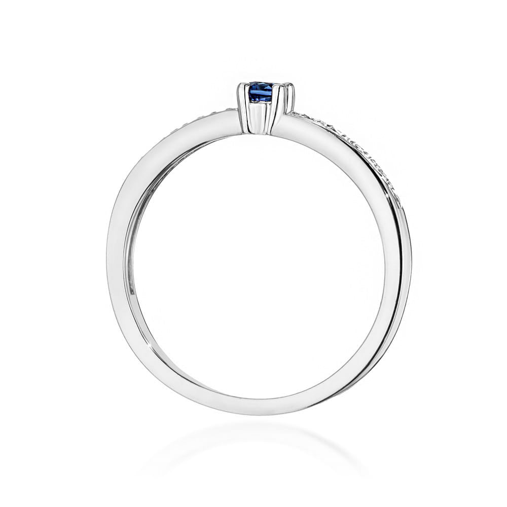 Ein Verlobungsring aus 585er Weißgold mit einem runden blauen Saphir als Hauptstein und kleineren Diamanten entlang der Ringschiene. Der Kontrast zwischen dem kühlen Weißgold und dem blauen Saphir ist deutlich sichtbar.