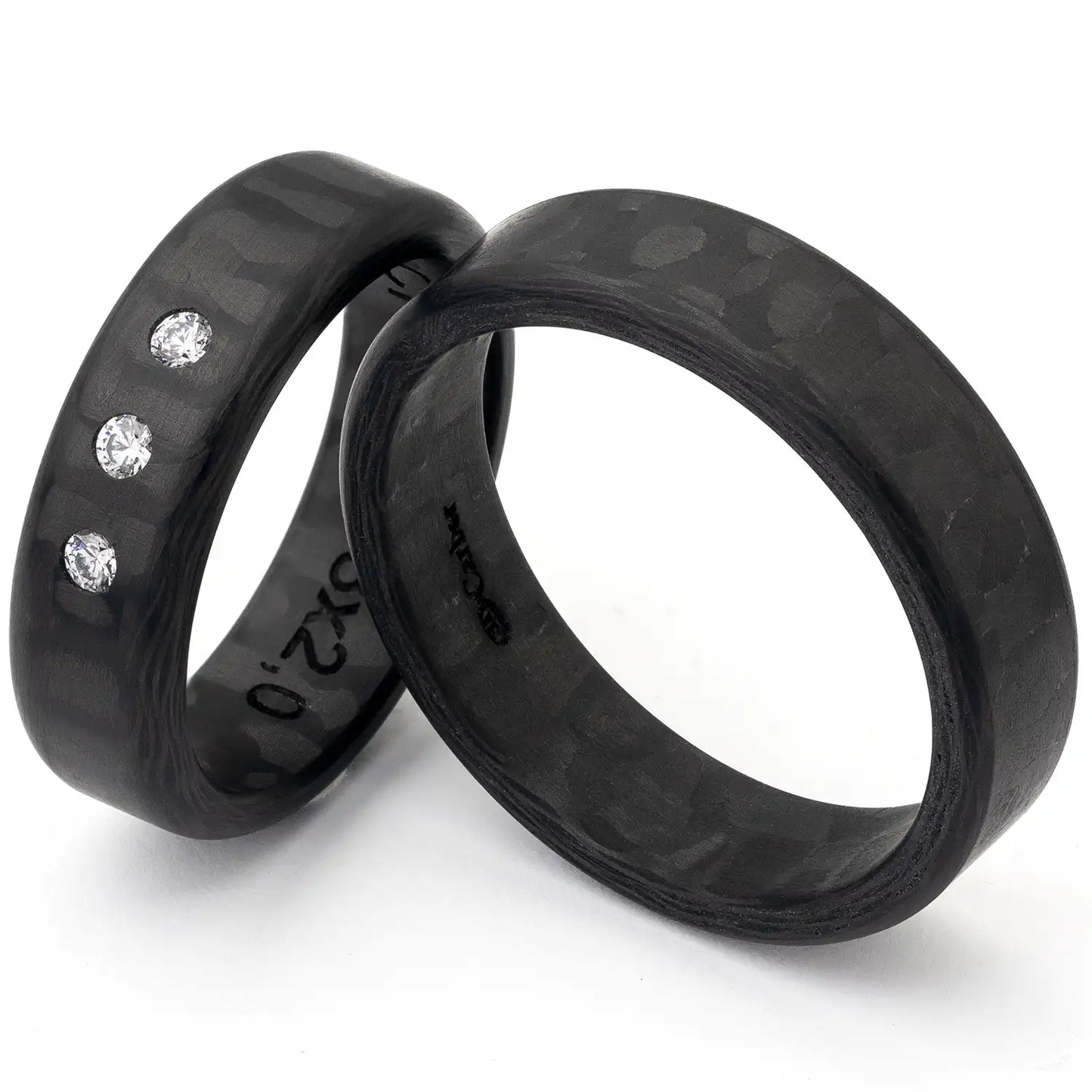 Zwei schwarze Carbon Eheringe, einer mit drei Diamanten.