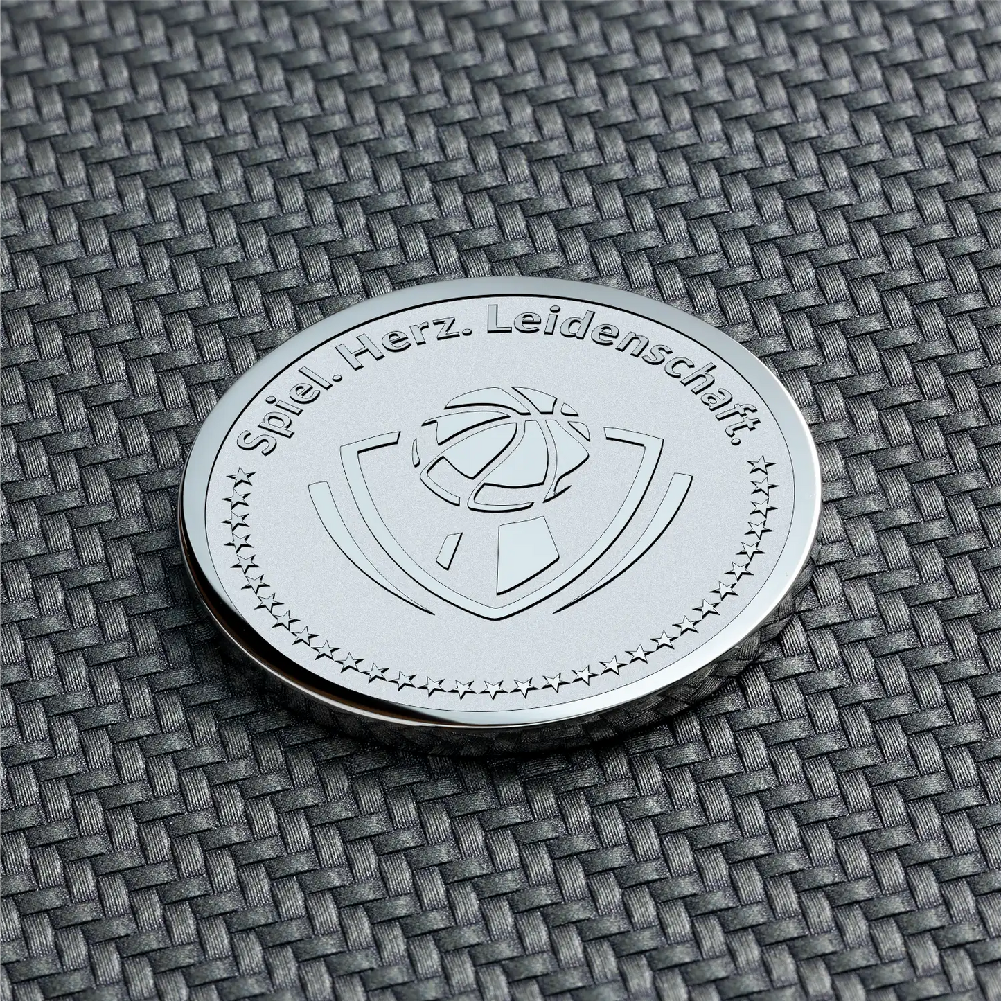 Gravierte Münze mit Basketball-Symbol und Text „Spiel. Herz. Leidenschaft.“