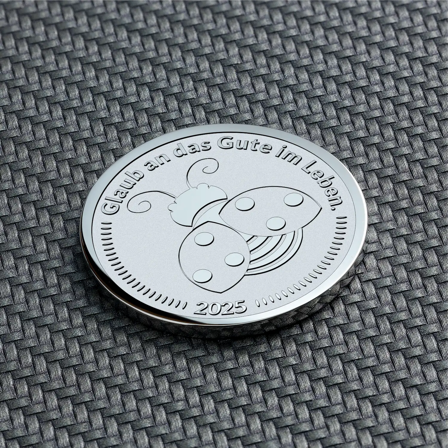 Gravierte Münze mit Marienkäfer und dem Text „Glaub an das Gute im Leben“