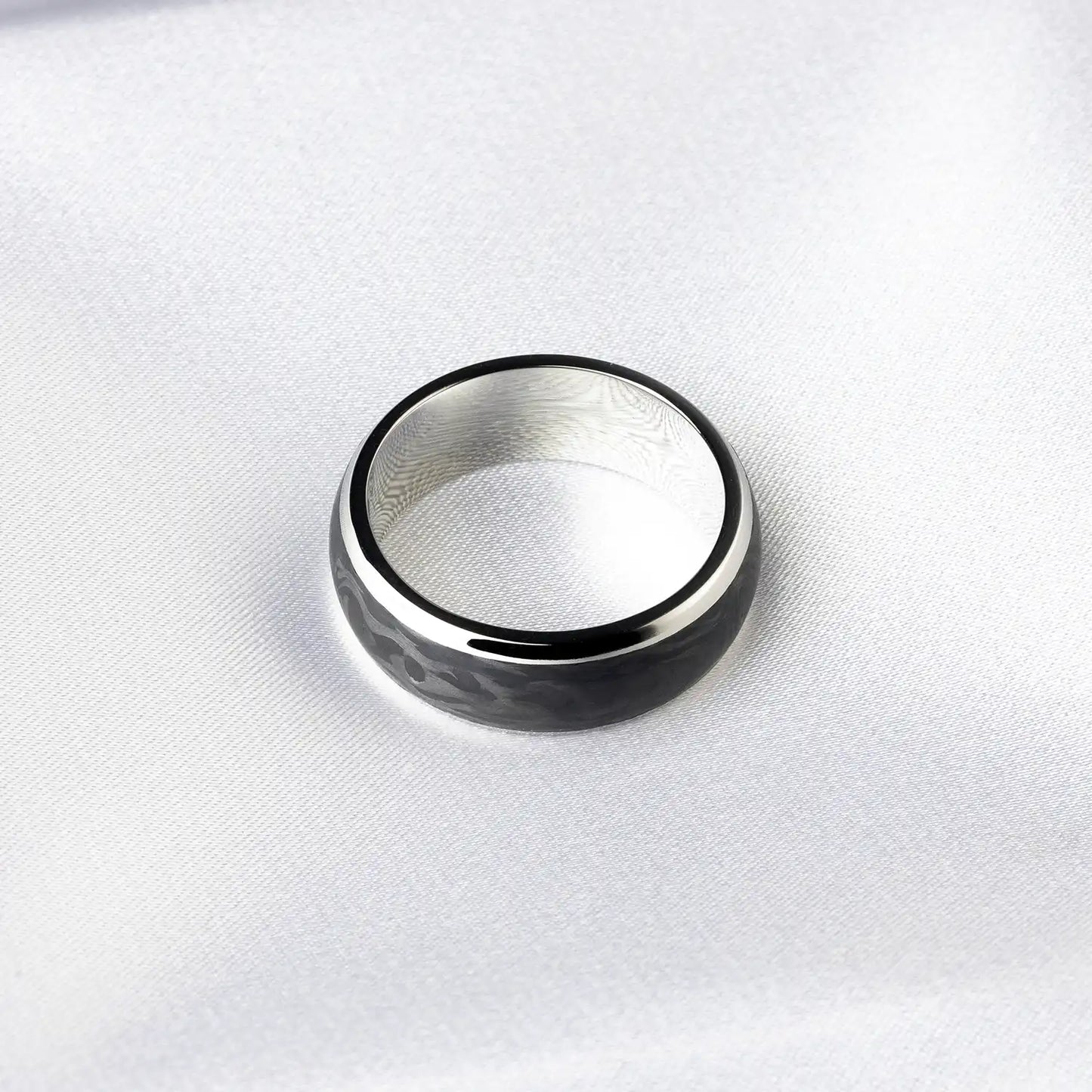 Schwarzer Titan- und Carbonfaser-Ring auf weißem Stoff
