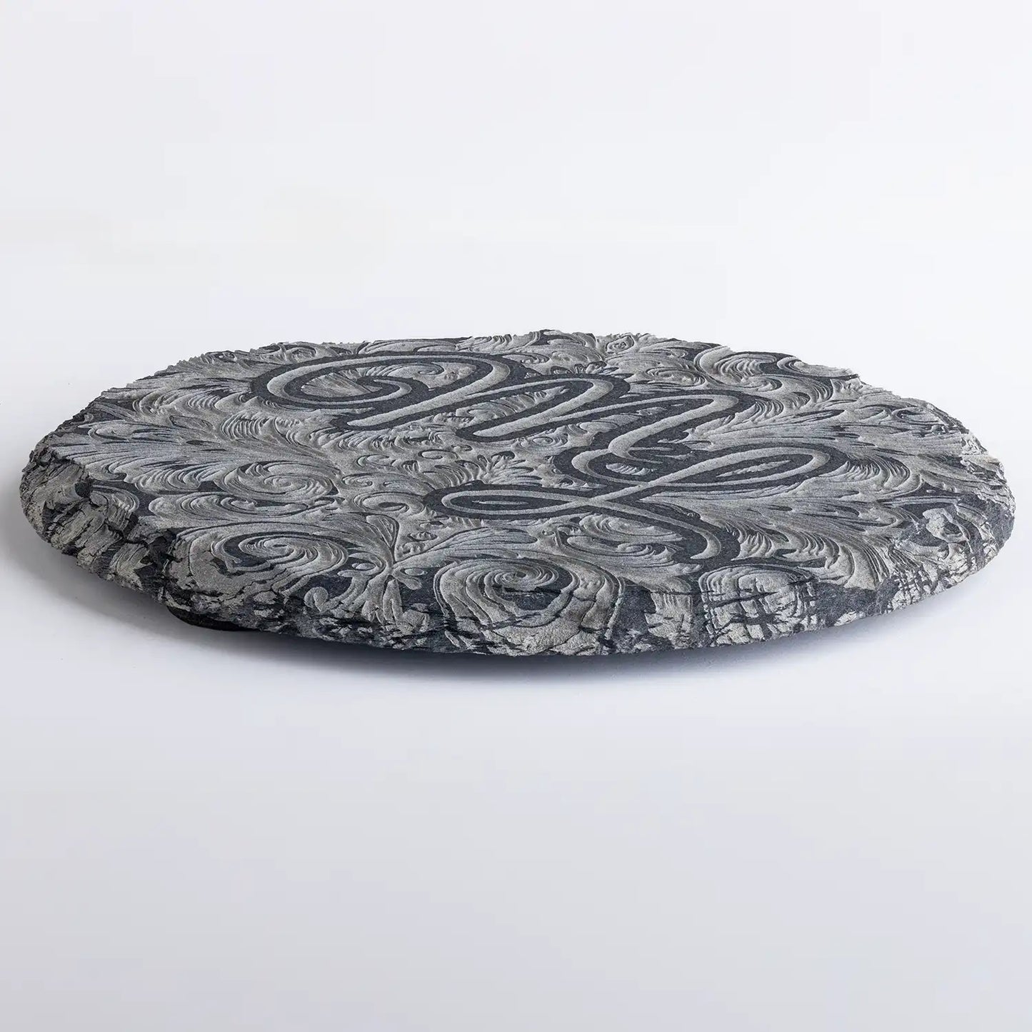 Runde Schieferuntersetzer mit kunstvoll graviertem Monogramm und dekorativen Ornamenten – einzigartiges Design für stilvolle Tischdekoration.
