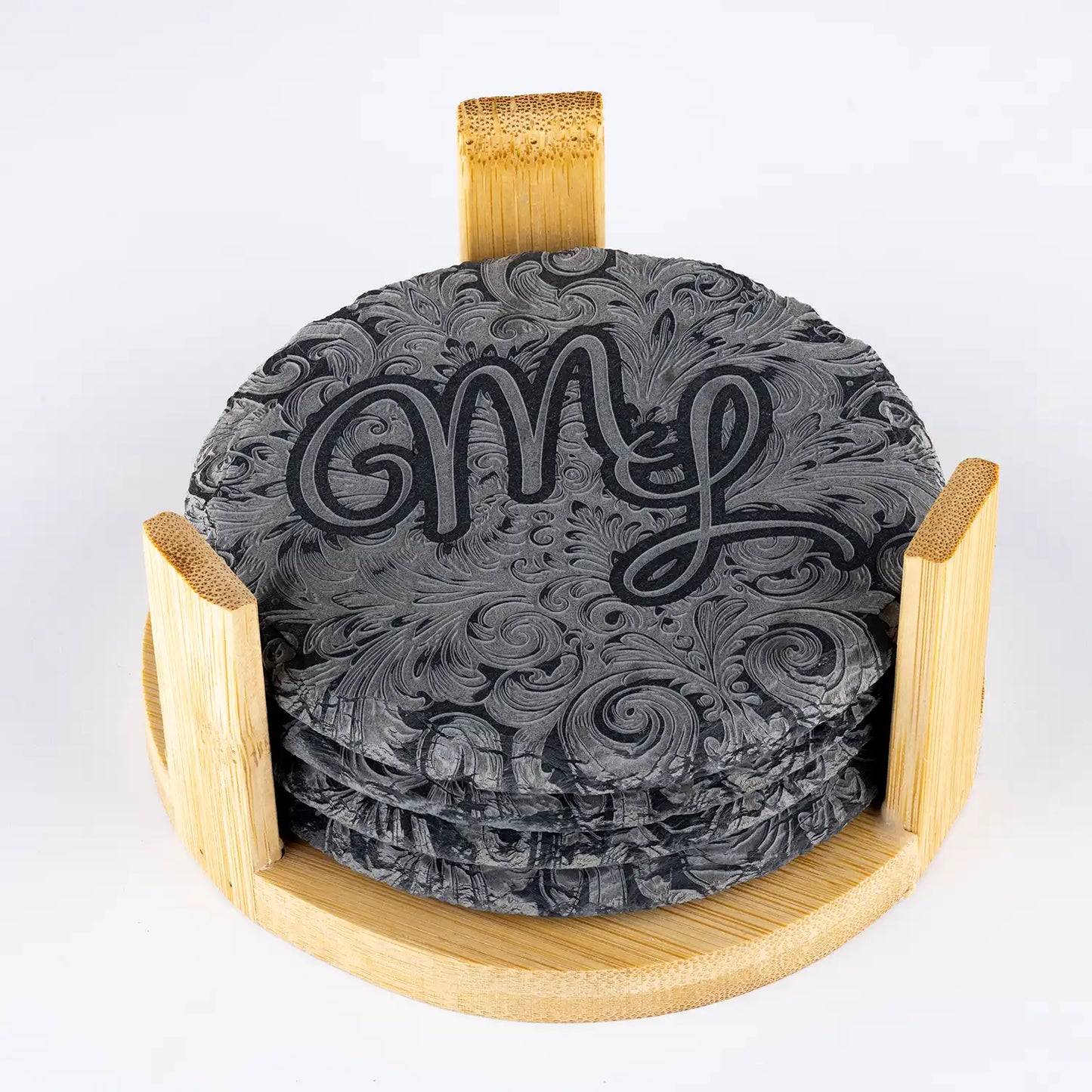 Set aus gravierten Schieferuntersetzern mit Monogramm, präsentiert in einem eleganten Holzhalter – perfekte Geschenkidee für Liebhaber personalisierter Accessoires.