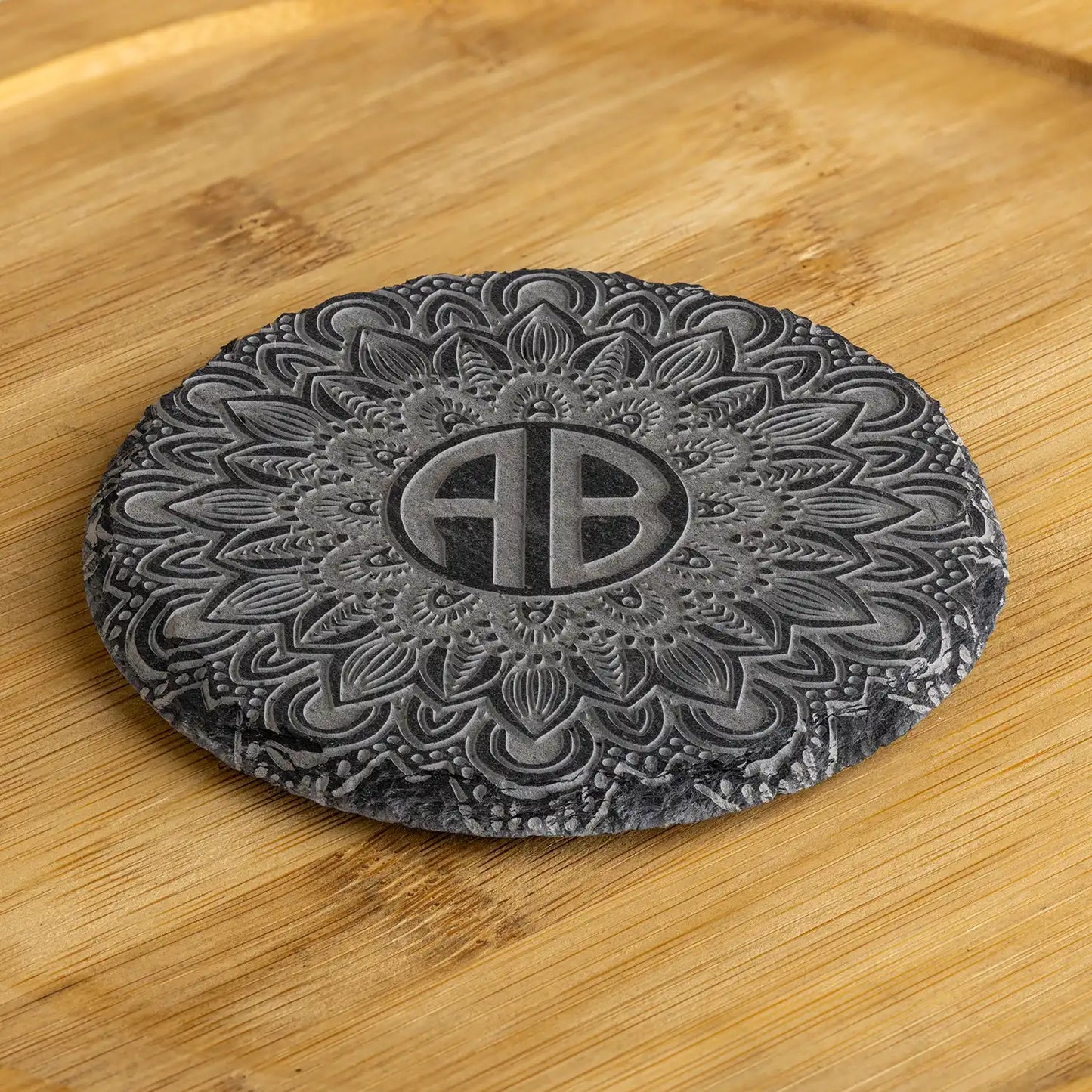 Personalisierter Schieferuntersetzer mit kunstvoller Gravur und Monogramm in der Mitte – einzigartiges Geschenk für stilvolle Tischdekoration.