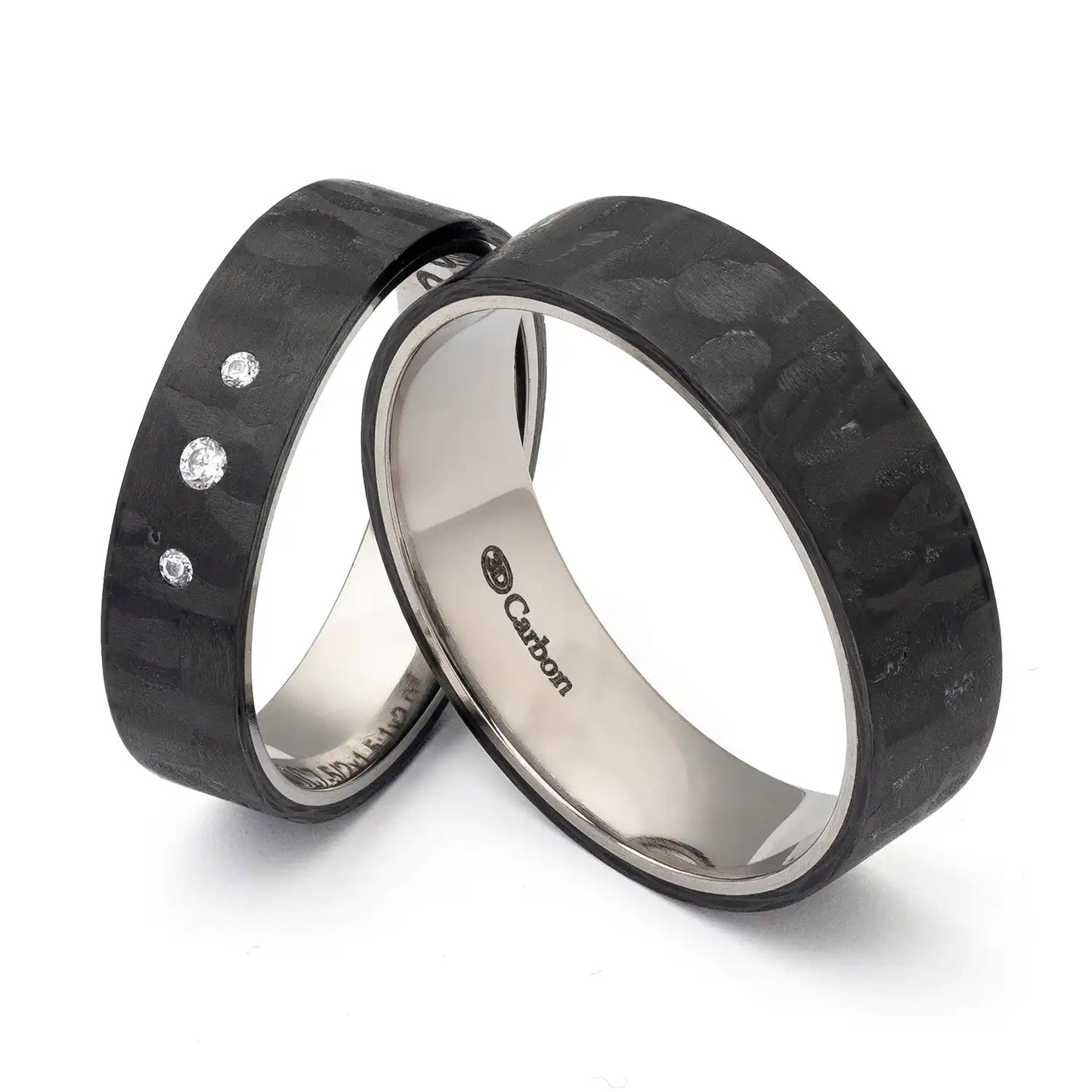 Zwei schwarze Carbon und Titan Eheringe mit glänzenden Oberflächen, wobei der Damenring drei kleine Zirkonia-Steine hat. Die Innenseiten sind glänzend und tragen das Carbon-Logo.