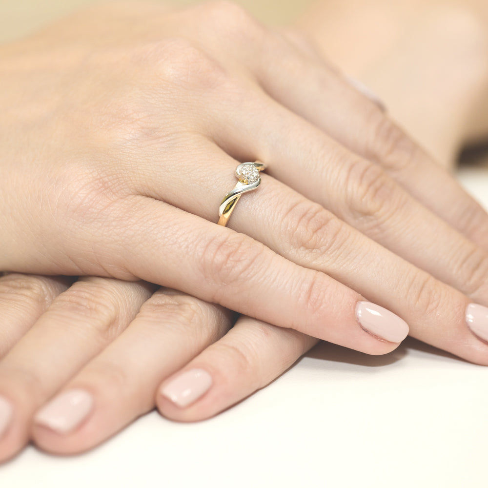 Dieser Verlobungsring aus Gold 585 hat eine elegante, geschwungene Form. Er ist mit sieben funkelnden Diamanten besetzt, die in einer Cluster-Fassung angeordnet sind. Die Hand auf dem Bild trägt den Ring, was seine Größe und Proportionen deutlich macht.