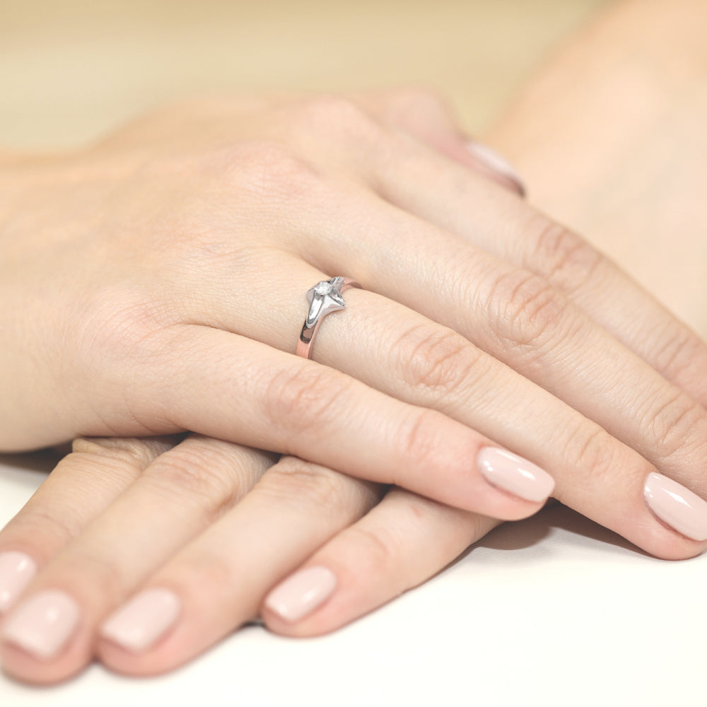 Die Nahaufnahme zeigt zwei Hände mit manikürten Fingernägeln. Eine der Hände trägt einen eleganten Verlobungsring aus Gold 585 mit einem Diamanten in einer stilvollen Fassung.