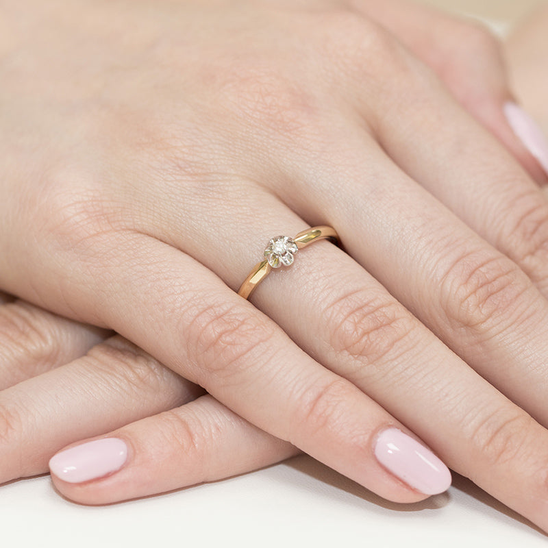 Dieser 585 Gold Verlobungsring hat einen funkelnden Diamanten und sitzt elegant am Finger. Die Hände sind gepflegt und die Nägel sind dezent lackiert.