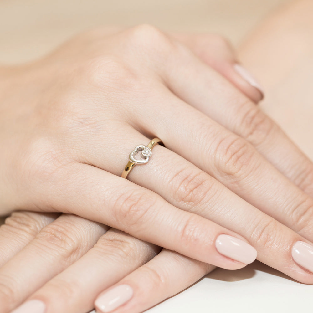 Ein wunderschöner Verlobungsring aus 585er Gelbgold mit zwei ineinandergreifenden Herzen und drei funkelnden Diamanten. Der Ring wird an einer Hand getragen und zeigt eine elegante und filigrane Verarbeitung. Perfekt für besondere Anlässe.