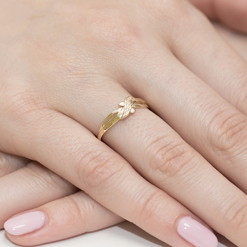 Verlobungsring aus Gelbgold 585 mit drei Diamanten auf dem Finger einer Hand. Der Ring hat ein filigranes und elegantes Design, das sich um den Finger windet und von funkelnden Steinen verziert wird.