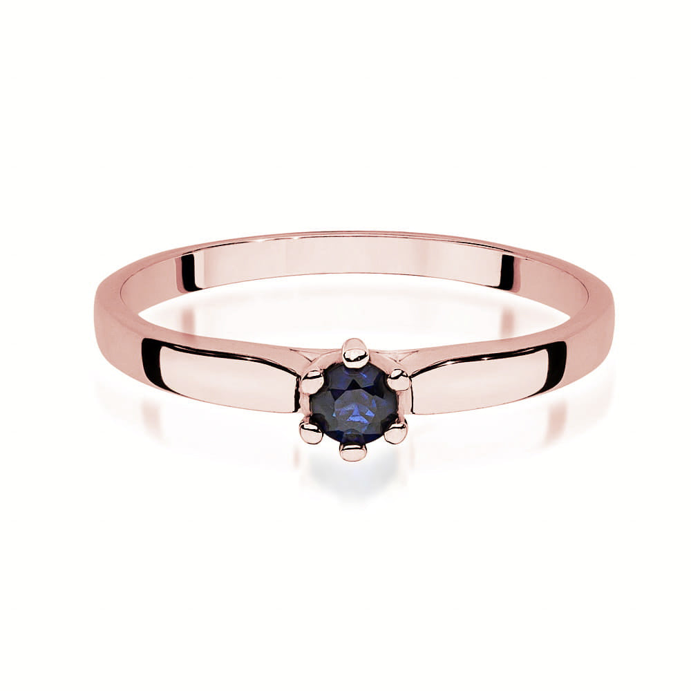 Ein seitliches Profil eines Rotgoldrings mit einem blauen Saphir in einer Krappenfassung. Die Ansicht zeigt die detaillierte Verarbeitung und das schlanke Band des Rings.