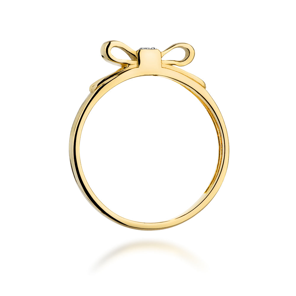 Ein seitlicher Blick auf einen Goldring mit einer Schleife und einem kleinen Diamanten. Der Ring hat ein schlichtes und glänzendes Design, das seine Eleganz unterstreicht.
