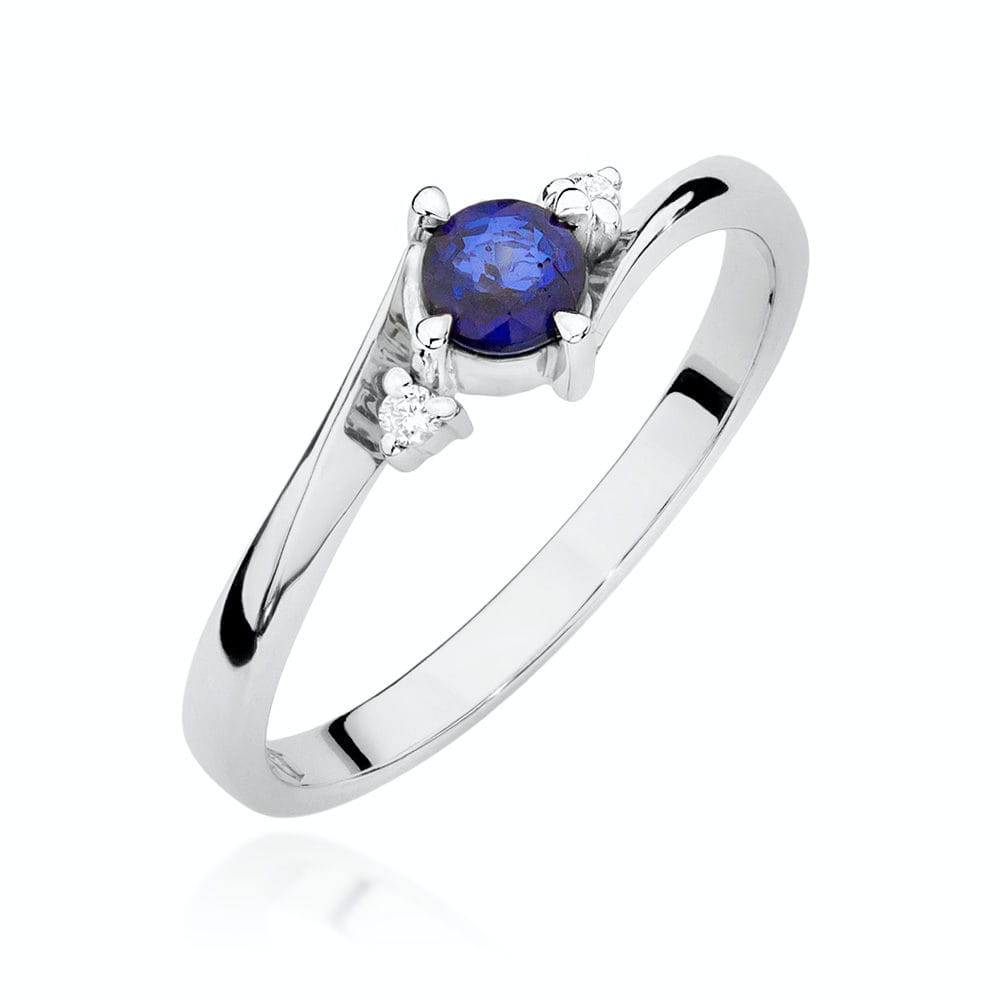 Nahaufnahme eines Verlobungsrings aus Weißgold 585 mit einem runden blauen Saphir und zwei kleinen Diamanten an den Seiten, die das Design betonen.