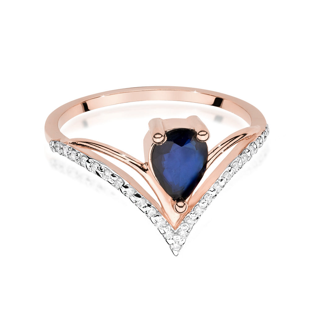 Hier sieht man einen Verlobungsring aus Roségold mit einem birnenförmigen blauen Saphir und 24 Diamanten. Der Ring ist frontal dargestellt und zeigt die V-Form und die funkelnden Diamanten entlang der Schiene.