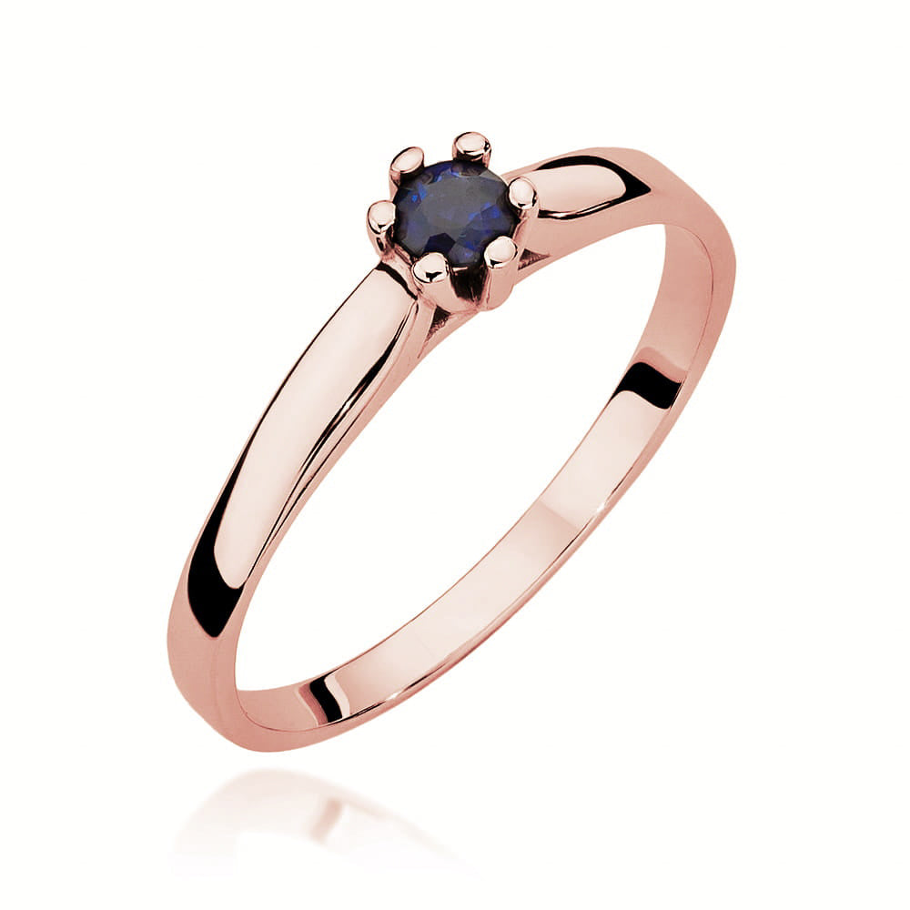 Ein Verlobungsring aus Rotgold mit einem zentralen blauen Saphir in einer klassischen Krappenfassung. Der Ring ist glänzend und detailreich abgebildet.