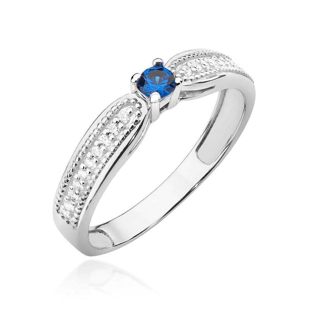 Ein wunderschöner Verlobungsring aus 14K Weißgold mit einem blauen Saphir und Diamanten. Der zentrale Saphir ist kunstvoll in das Band eingefasst.